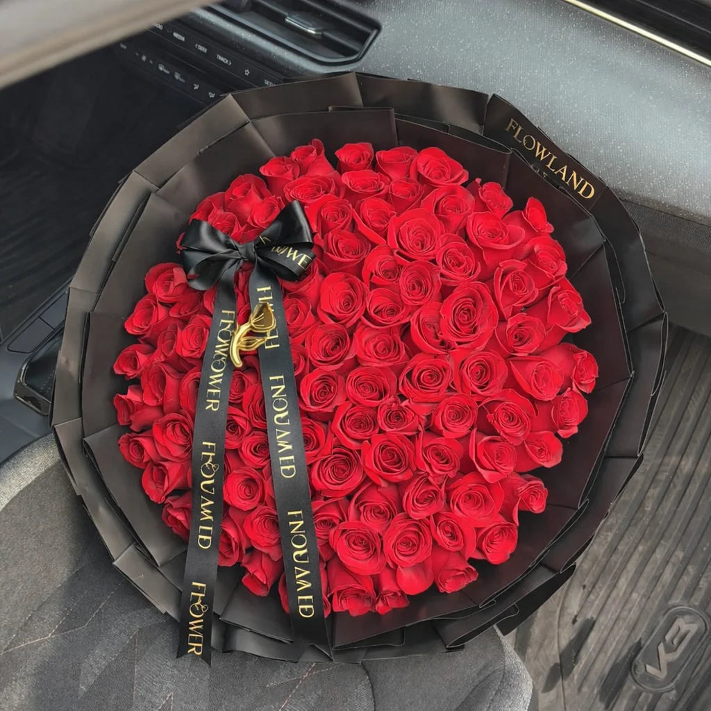Luxury Ramo Buchón with red roses arranged in a rounded bouquet, wrapped in black paper and finished with a black and gold Flowland ribbon.
