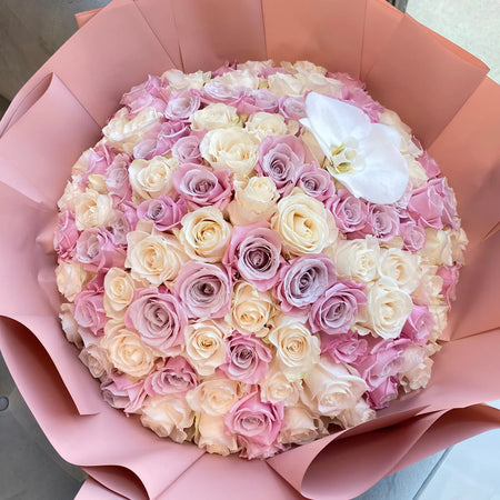 Lady in Pink Ramo Buchón with pastel pink and cream roses, a white orchid accent and blush pink wrapping.
