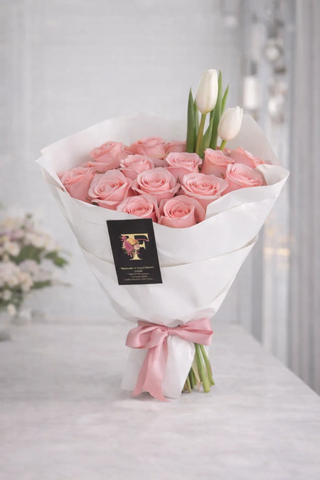 Soft Blush Bouquet with pink roses and two white tulips, wrapped in white paper and tied with a pink satin ribbon.