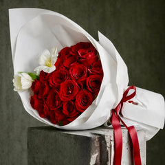 The Velvet 25 bouquet with red roses and white tulips, wrapped in white paper and tied with a red satin ribbon.